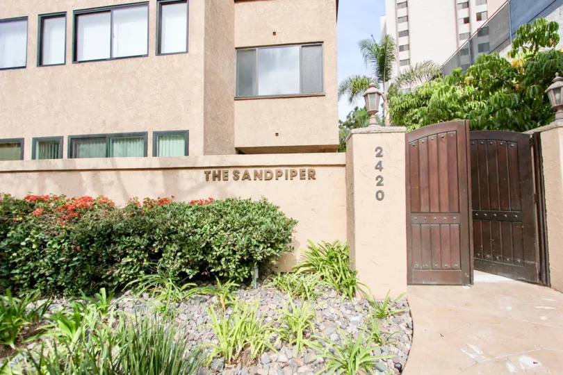 Brown sign on a pink wall near pink condos inside Sandpiper in La Jolla California