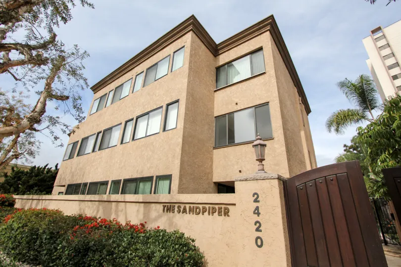 In The Sandpiper, a bush with flower in the entrance and Apartment has 3 floors