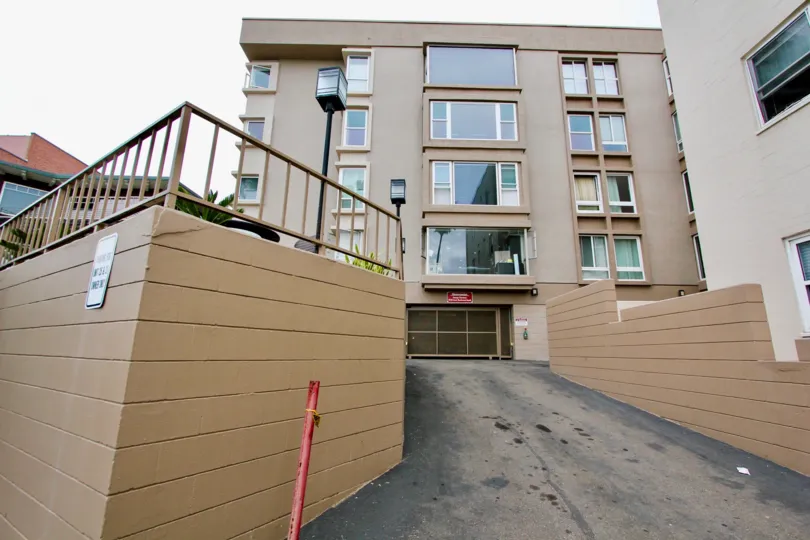 A five story apartment complex with big windows in an urban area. The picture was taken from a back alley