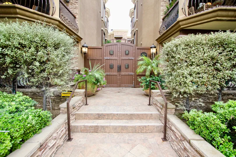 A pleasant scene of shrubbery along a path leading to a gated alley in La Jolla, Venezia