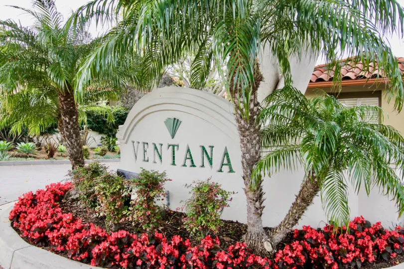 A concrete signage painted in white in the Ventana neighborhood surrounded by red plants.