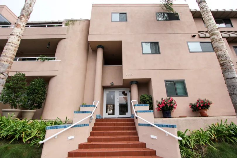 A front entrance to a building with a nicely laid out brick stairs in the Villa Italia community. The setting is in La Jolla California.