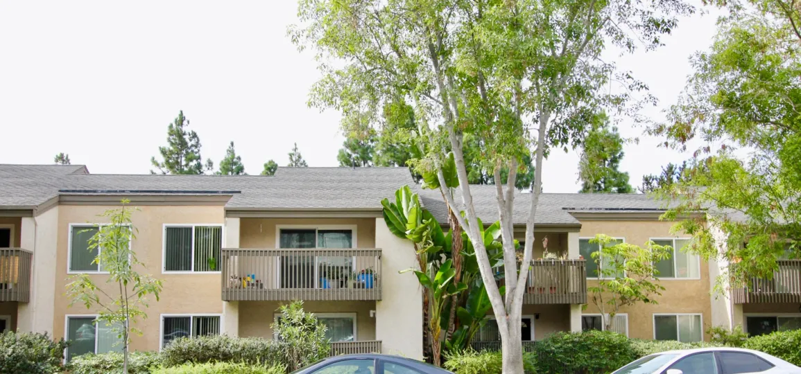 The street in the Villa La Jolla has many villas with trees and car parking the road