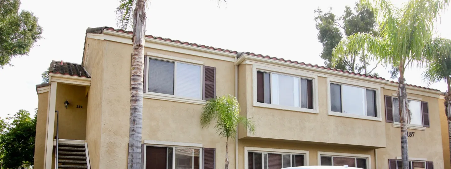 Two story white building with windows & palms in Villa Tuscana in La Jolla California