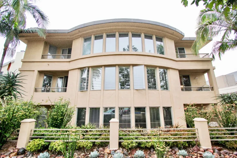 The view of the building with the trees, plants and has three floors in the builiding