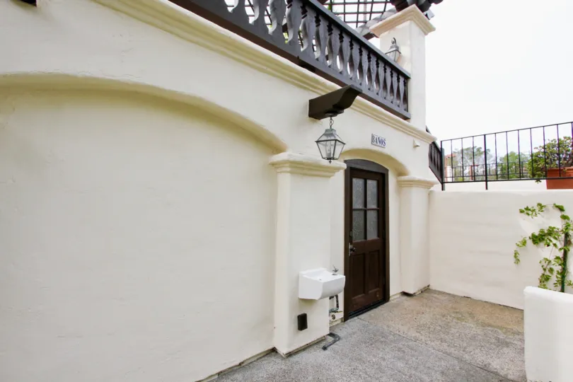 Black door next to a hanging lantern and wall at Villas Mailorca in La Jolla CA