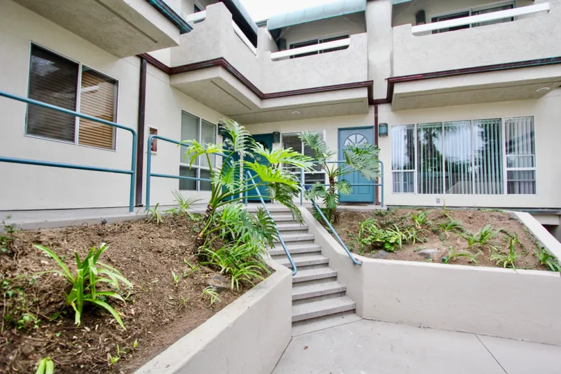 A white entry way with blue trim and palm trees at Wind N Sea