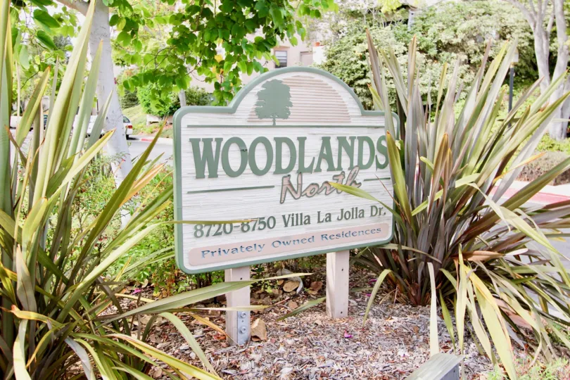 Wooden sign with green and pink writing inside Woodlands North in La Jolla CA