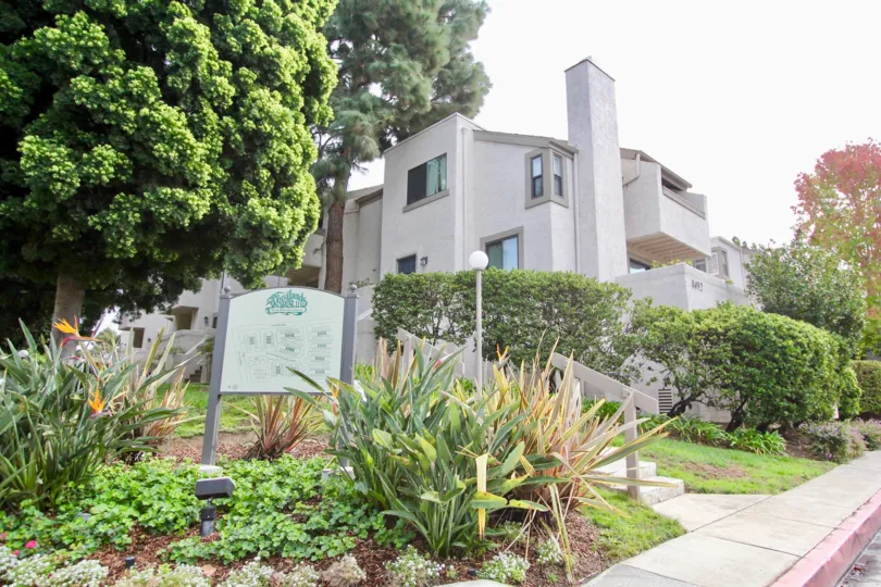 THE BUILDING IN THE WOODLANDS WEST II WITH THE PATHWAY, TREES, PLANTS, BOARD