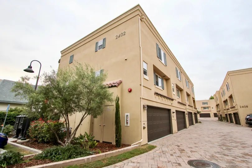 Three story brown building with garages & tiled driveway in Ziani in La Jolla CA