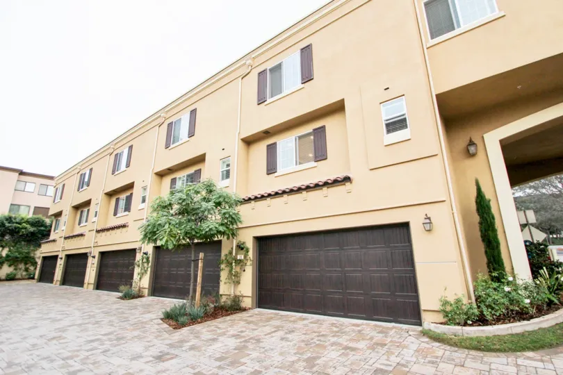 Dark brown garage doors on pink residences inside Ziani in La Jolla CA