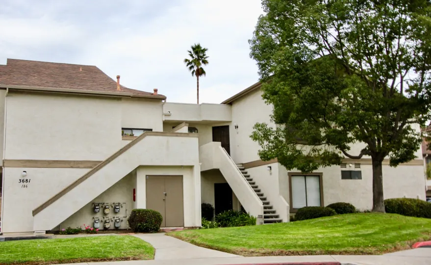 A cheerful day at Avocado Village in La Mesa with clean landscaping and a palm tree.