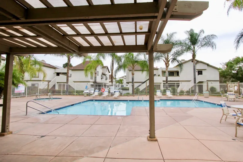 A panoramic view of a backyard swimming pool in La Mesa, CA, taken from beneath a wood-slat awning.