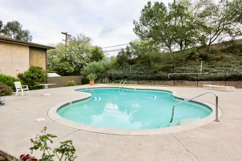 A beautiful swimming pool in the Brierwood Village with trees and plants.