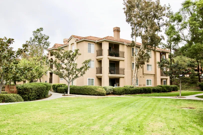 A sunny day in the Central Park La Mesa with a big apartment and trees.