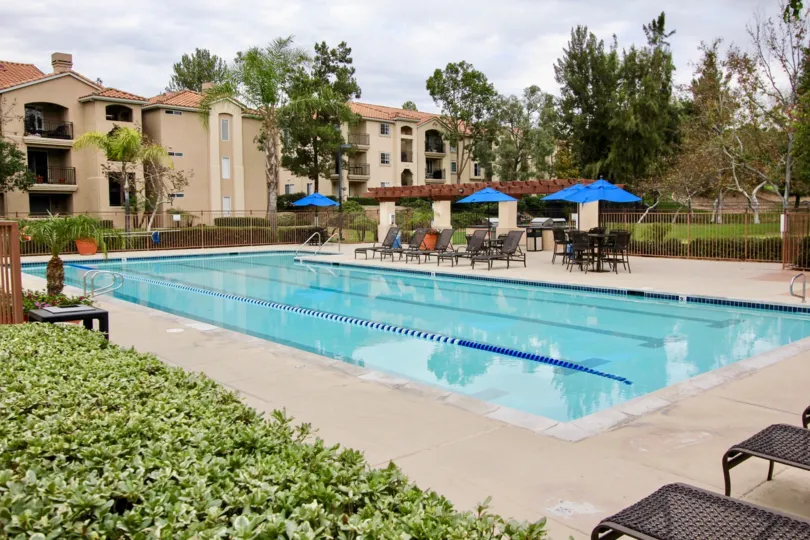 Private swimming pool for residents with a lap lane and ample space on the pool deck with mature trees in La Mesa
