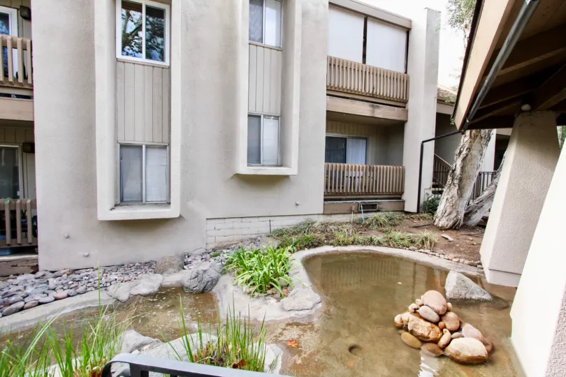 An entrance of a building in the La Mirianda with beautiful plants and pool.