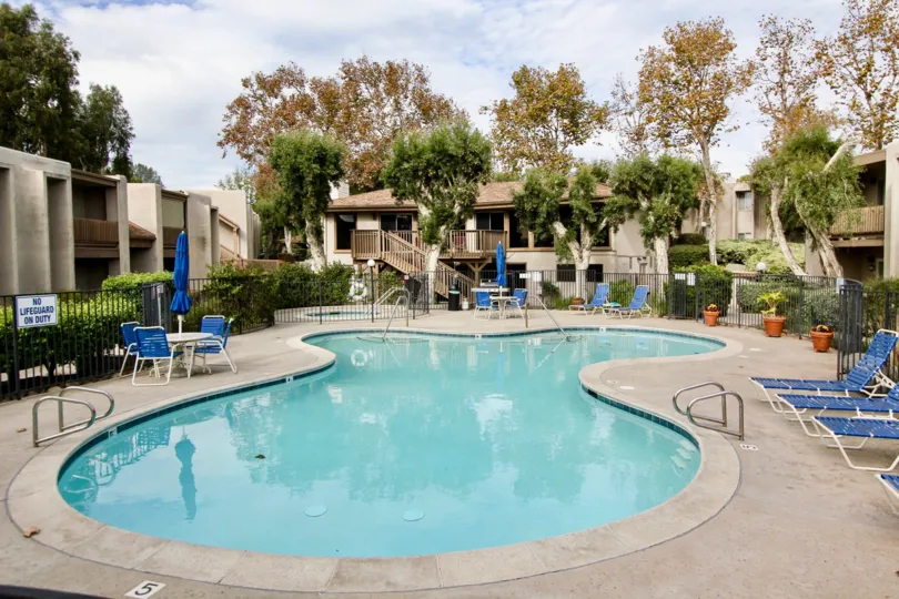 The La Mirianda with blue chairs near the pool side and trees around