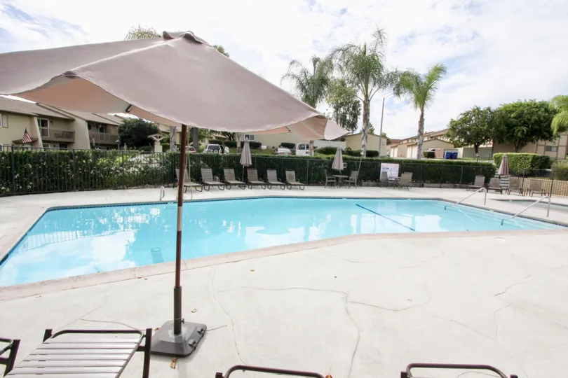 A long blue pool lined with lawn chairs inside Lake Glen Park at La Mesa California