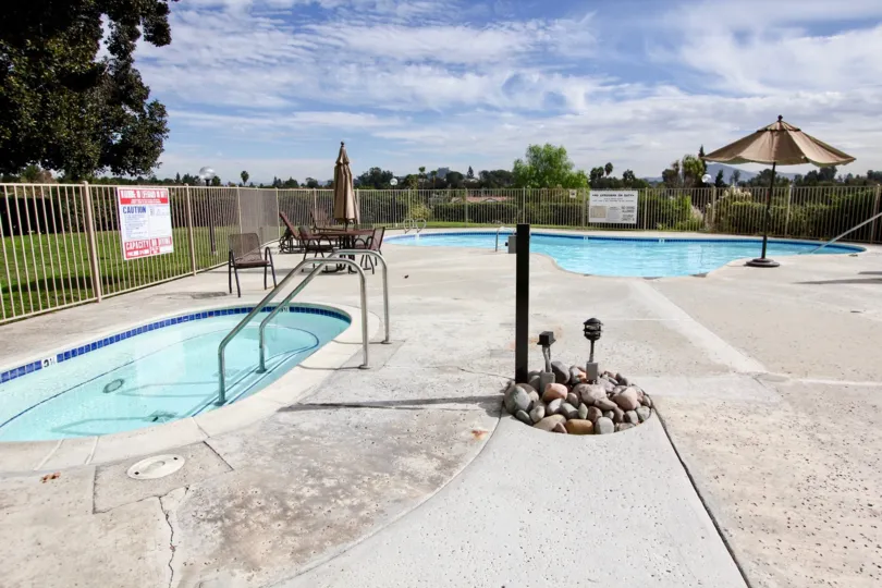 THIS IMAGE SHOW THAT SWIMMING POOL IN THE LAKE PARK WHICH HAS BEEN STONES, TABLES, TREES, PLANTS