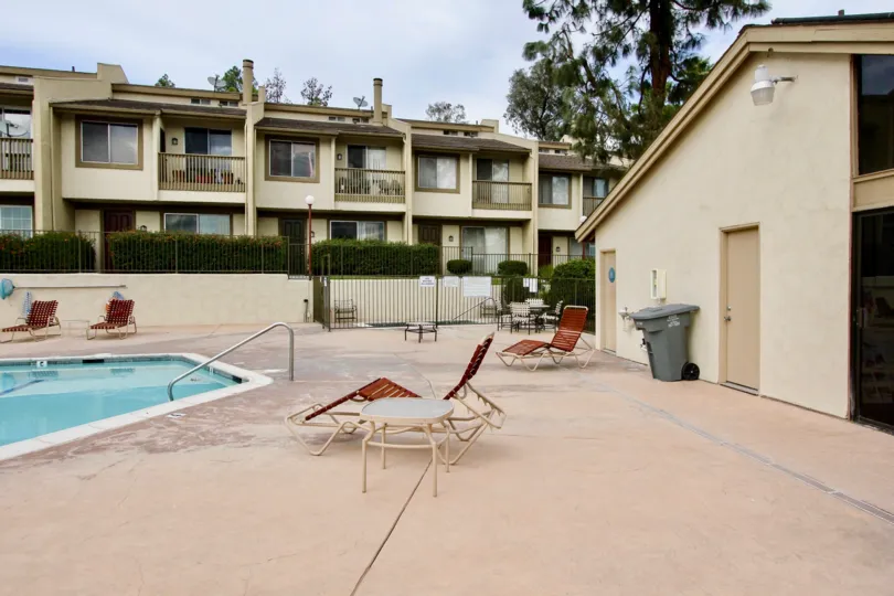 A SUNNY DAY IN THE PARKWAY VILLAS WITH THE SWIMMING POOL, BUILDING, TABLES, DUSTBIN