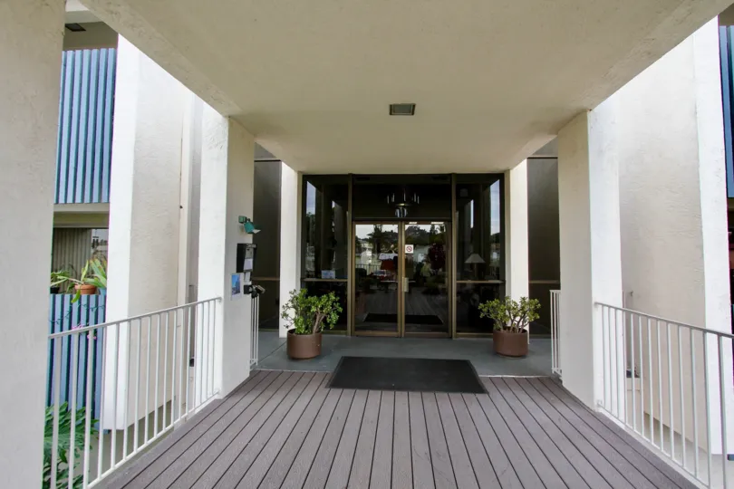 A walkway made out of wood with a large black mat leading to Rosehedge Manor in La Messa CA