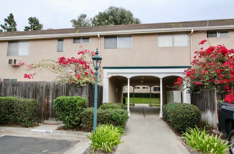 The front side of Westwood Village with tall flowring plants and grass around
