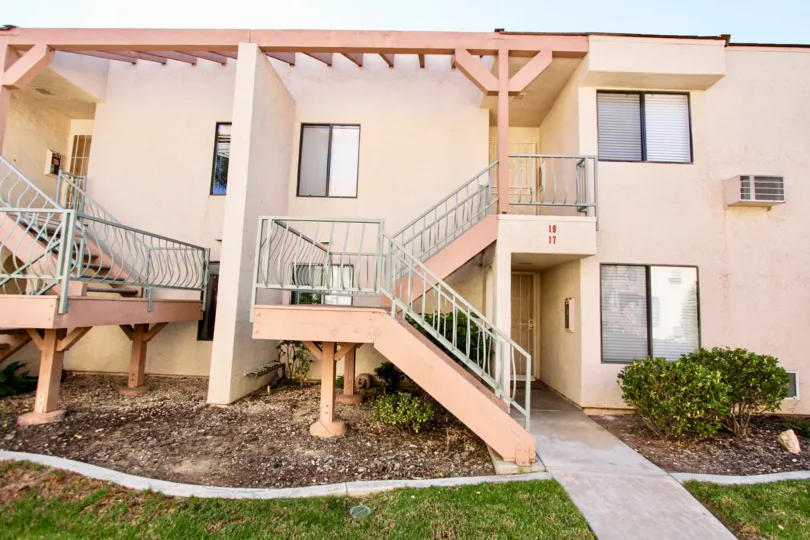 The backside of the house which have the steps and glass windows and have the onepathway, plants are grown up in the community of Casa New Salem