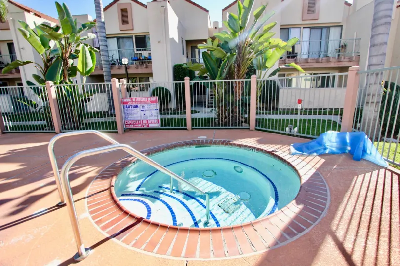 A sunny day poolside in the area of Casa New Salem, hot tun, fence, trees, codps. balconies