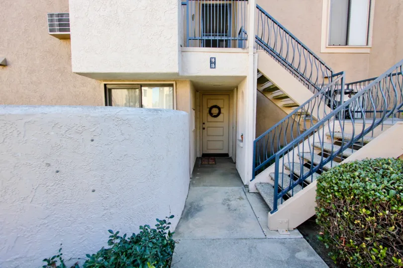 A front wooden door of a house in an apartment building with a stairs in front of it at Flair community