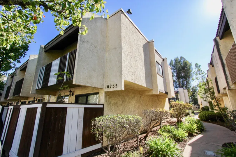 The side of several apartment buildings with a small garden and path running through in the Gold Creek area of Mira Mesa, California