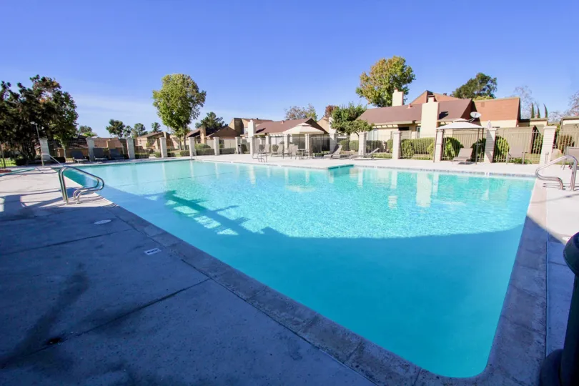 A sunny day with a swimming pool in between the villas with trees around in Mesa Village of Mira Mesa