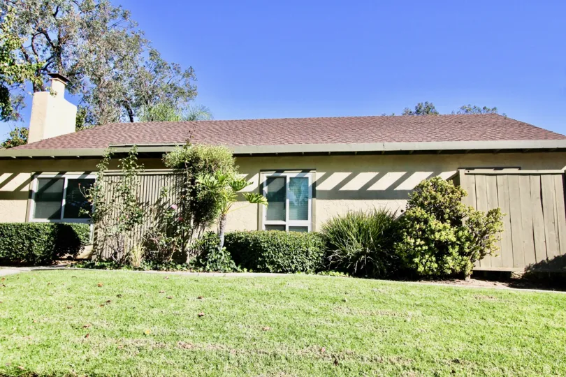 A sunny day with green lawn and trees outside a house in Mesa Village of Mira Mesa