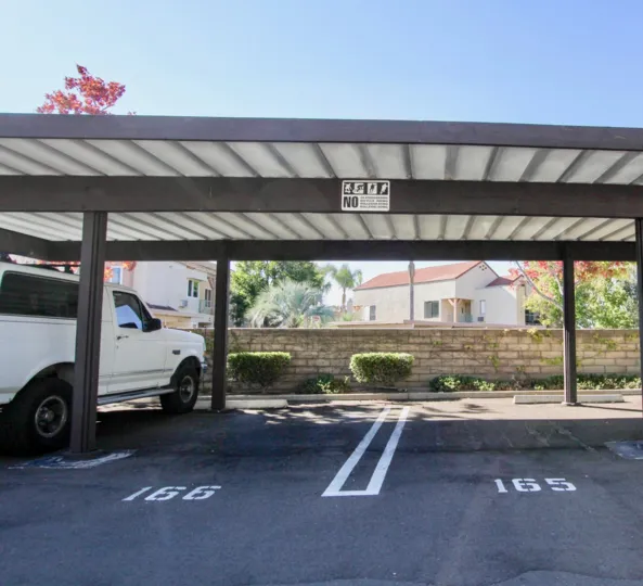 A SUNNY DAY IN THE VILLAS AT NEW SALEM WITH A CAR PARKING THAT HAS WHITE COLOURED CAR IN IT.