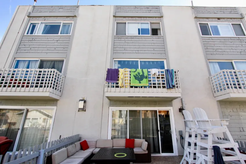Three story gray building with towels hanging from a balcony at 711 Island Court in Mission Beach CA