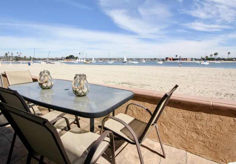 The beach and ocean view from the Carmel Villas with sand, water, and boats in a marina.