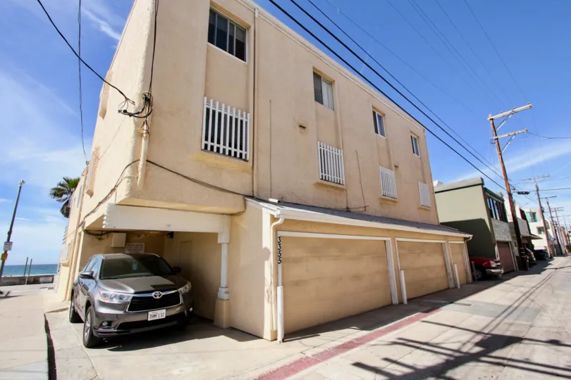 Three story residential units with car parked next to them inside MB Townhomes at Mission Beach CA