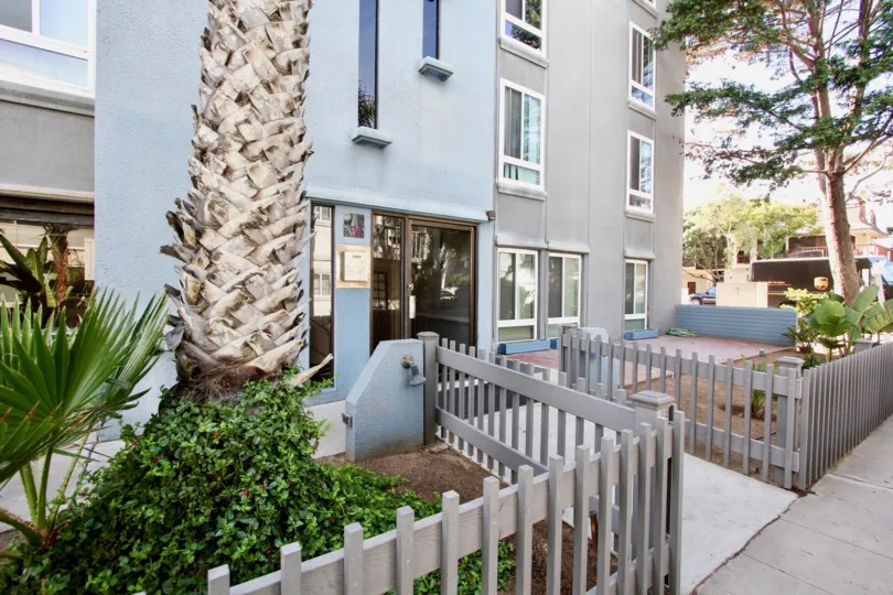 A gray picket fence encloses landscaping at Mission Beach Towers