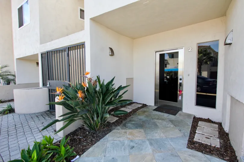 An entryway with glass doors and tropical plants at Mission Beach Villas