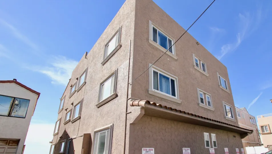Three story brown building with a stubby roof inside Mission Belle at Mission Beach CA