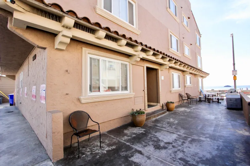 A sunny day in Mission beach with the patio of a mission-style house with chairs and a view of the beach