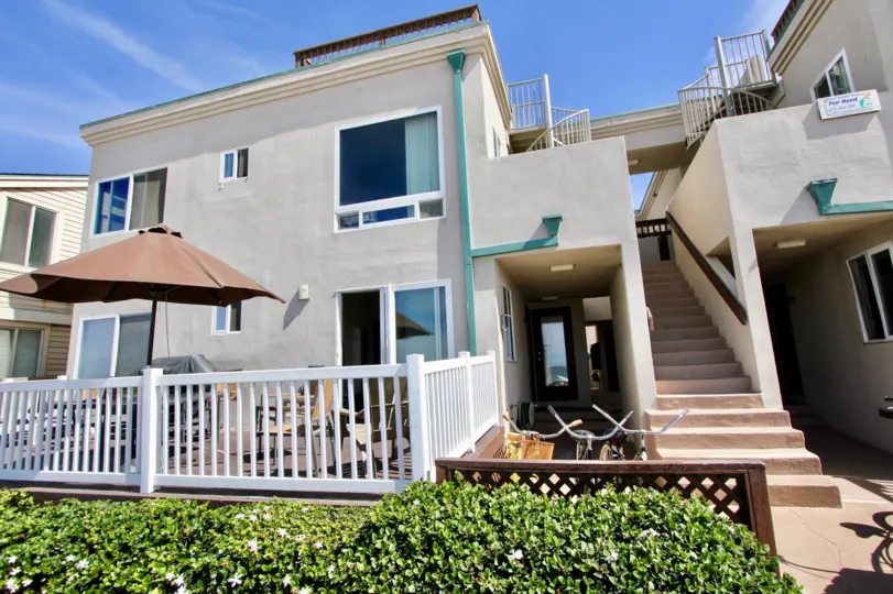 Two story building with a white railing with plants out front in Ocean Front Breakers at Mission Beach CA