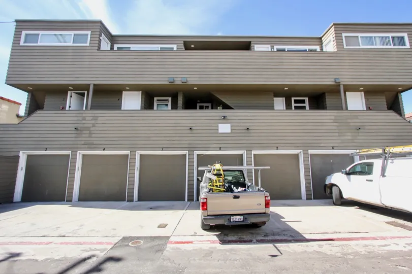 A pickup truck filled with tools is parked in front of the Ocean West condos