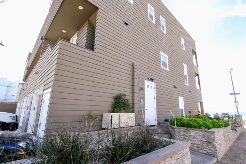 The exterior of the brown wood sided Ocean West building with private garages and exterior stairs.