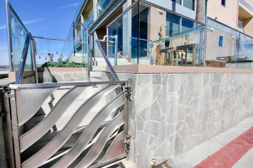 A gateway with glass railing and a stone wall in San Juan Condominiums