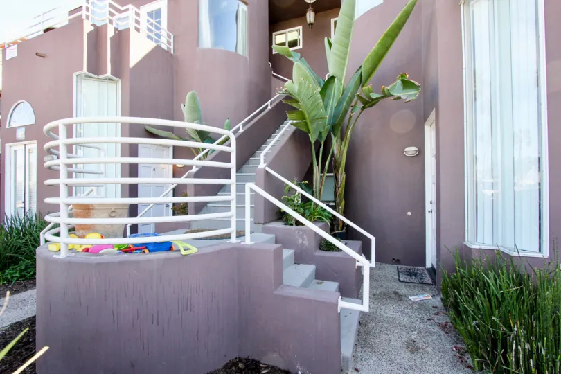 STAIRCASE IN APARTMENT/CONDO UNIT WITH KIDS TOYS AND ROUNDED BANISTER