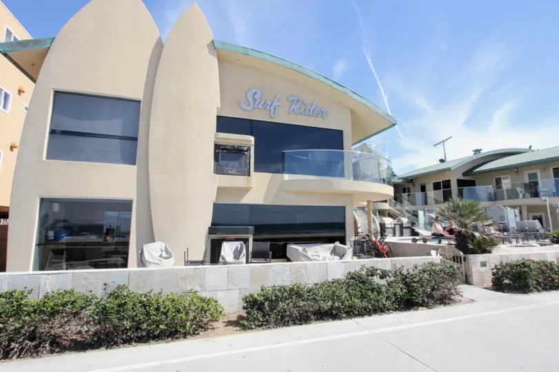 The face of the Surf Rider building with sun bathers in lawn chairs out front.