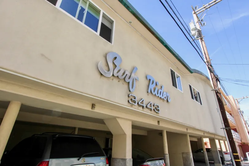 Covered parking areas underneath blue sky as seen from the alley view of Surf Rider residences in Mission Beach, CA.