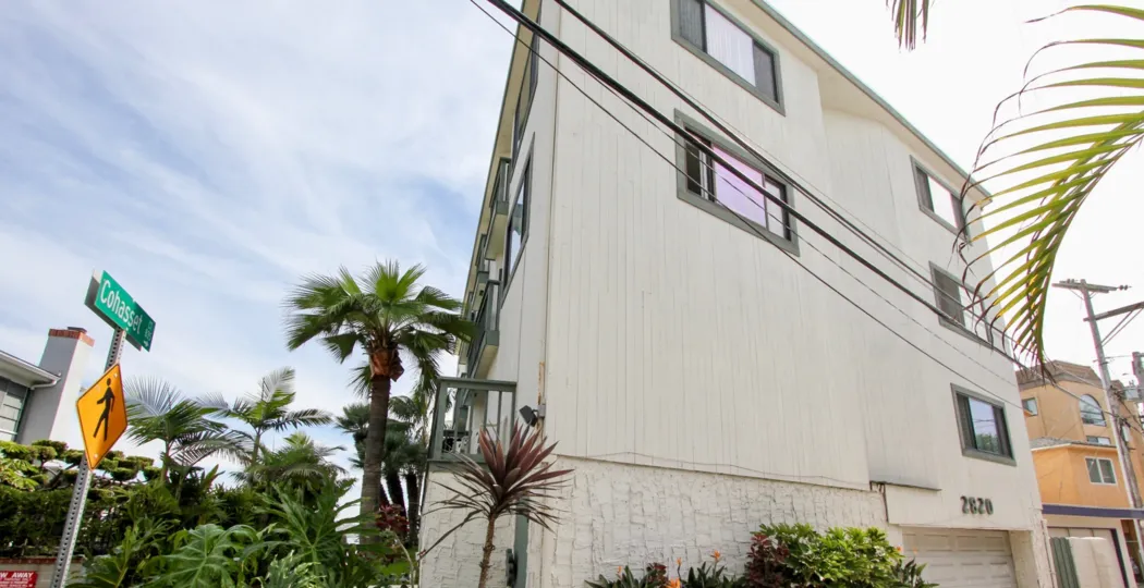 A white wood sided apartment home fronted by palm trees on Cohasset in The Fijian community.
