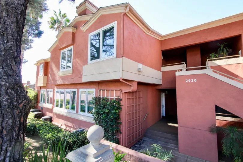 The exterior view of the red stucco Columbia Crest building including the stairs, trellis, and wide windows.